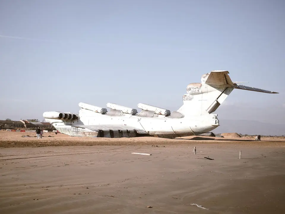 Ein großes sowjetisches Ekranoplan ruht an einem Küstenstrand, ein Relikt der Militärgeschichte.